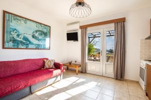 ein Wohnzimmer mit einer roten Couch und einer Glasschiebetür in der Unterkunft Venetia's Garden in Lefkos Karpathos