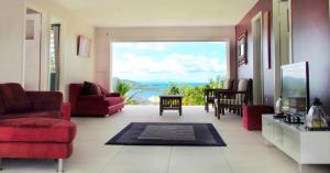 a living room with red chairs and a large window at LADILAFE in Le Marin