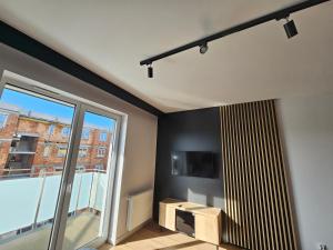 ein Wohnzimmer mit einem TV und einem großen Fenster in der Unterkunft Apart Family Lębork in Lębork