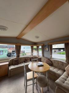 ein Wohnzimmer mit einem Sofa und einem Tisch in der Unterkunft Spacious 2 bedroomed mobile home in Aberystwyth
