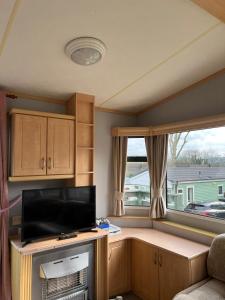 ein Wohnzimmer mit einem TV und einem Fenster in der Unterkunft Spacious 2 bedroomed mobile home in Aberystwyth