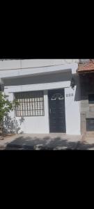 Casa blanca con puerta y ventanas negras en Los Maitenes 888 en Chos Malal