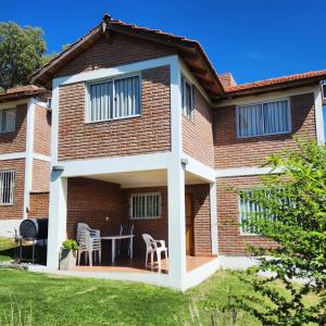 a brick house with a patio and two chairs at C&W Vacaciones Diferentes in Villa Carlos Paz