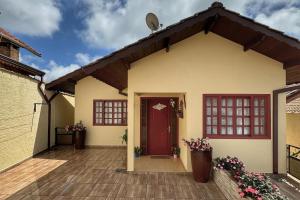 ein Haus mit einer roten Tür und ein paar Blumen in der Unterkunft Casa Luar in Monte Verde