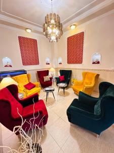 a living room with colorful furniture and a chandelier at Hotel Korona Wellness, Rendezvény és Borszálloda in Eger