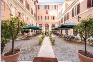 eine leere Straße mit Sonnenschirmen, Tischen und Stühlen in der Unterkunft Relais Hotel Antico Palazzo Rospigliosi in Rom