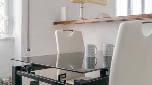 una mensola in vetro con due sedie bianche in una stanza di Italianway - Betti 46 a Rapallo Altre 21 foto