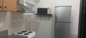 uma cozinha com um frigorífico de aço inoxidável e um micro-ondas em Mono Ambiente C em General José de San Martín