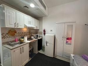 a kitchen with white cabinets and a sink and a refrigerator at The Regal Residency Studio, 1 Minute Walking Distance from Gold Souk in Dubai