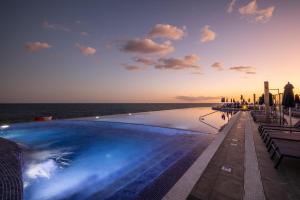 a swimming pool with the ocean in the background at Marina Suites Gran Canaria in Puerto Rico de Gran Canaria