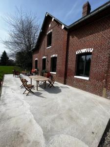 eine Terrasse mit einem Tisch und Bänken neben einem Backsteingebäude in der Unterkunft *Le Hameau Paisible : *Maison de Campagne* 