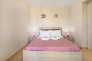 um quarto com uma cama com lençóis cor-de-rosa e duas velas cor-de-rosa em Iliovasilema Holiday House em Volímai
