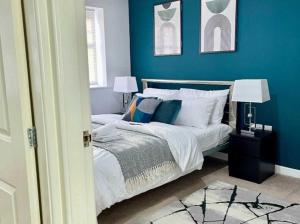 a bedroom with blue walls and a bed with pillows at Hutchinson House JCS Property in Birkenhead