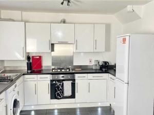 a kitchen with white cabinets and a white refrigerator at Hutchinson House JCS Property in Birkenhead