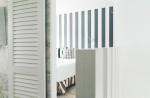 a bedroom with a white bed with a striped wall at Marina Bayview Gran Canaria - Adults Only in Puerto Rico de Gran Canaria