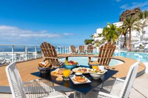 een tafel met eten en drinken naast een zwembad bij Marina Bayview Gran Canaria - Adults Only in Puerto Rico de Gran Canaria
