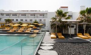 a hotel with a swimming pool and chairs and umbrellas at Buendía Corralejo nohotel in Corralejo