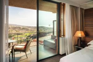 a bedroom with a bed and a balcony with a view at Salobre Hotel Resort & Serenity in Salobre
