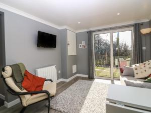 a living room with a couch and a tv at Caldwell Cottage in Lanark