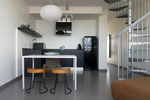 a kitchen with a table and two stools and a refrigerator at Buendía Corralejo Nohotel in Corralejo