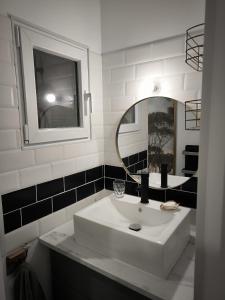 La salle de bains est pourvue d'un lavabo blanc et d'un miroir. dans l'établissement Maison en Baie Du Mont, à Roz-sur-Couesnon