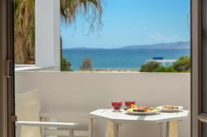un tavolo bianco con un piatto di cibo e due bicchieri di Glaronissi Beach a Plaka