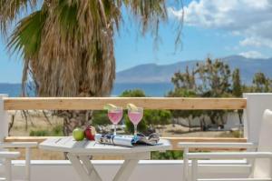 a white picnic table with two glasses of wine at Glaronissi Beach in Plaka