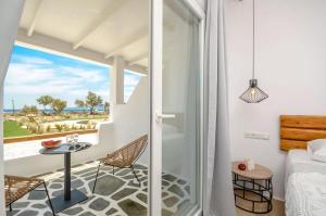 Zimmer mit einem Balkon, einem Bett und einem Tisch in der Unterkunft Glaronissi Beach in Plaka