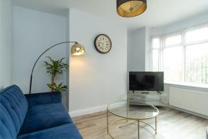 a living room with a blue couch and a clock on the wall at Heath House in Burton upon Trent +21 photos