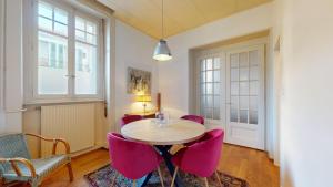 een eetkamer met een tafel en roze stoelen bij Authentic apartment in the heart of Vevey in Vevey