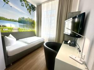 ビッターフェルトにあるHotel "Central" Inh Carolin Krauseのベッドとテレビが備わる小さなホテルルームです。