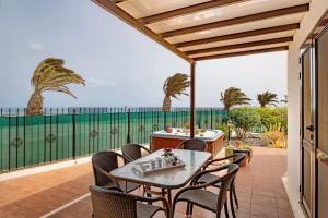 um pátio com uma mesa e cadeiras e o oceano em Villa Kanak em Puerto del Carmen