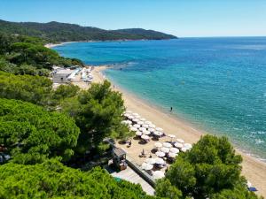 a beach with umbrellas and people on the beach at La Pinède Plage in La Croix-Valmer