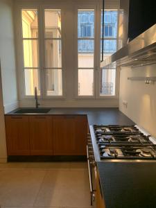 a kitchen with a stove and a sink and windows at 4 bedroom Luxury Eiffel Tower Apartment in Paris