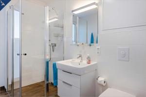 a white bathroom with a sink and a shower at Haffblick 1 in Zirchow