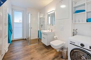 een badkamer met een toilet, een wastafel en een wasmachine bij Haffblick 1 in Zirchow