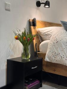 een vaas met bloemen op een nachtkastje naast een bed bij De Seuterhoeve in 's-Gravendeel
