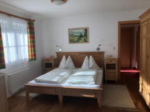 een bed met witte lakens en kussens in een kamer bij Schmiedlehnerhof in Birnberg