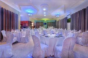 un salón de banquetes con mesas blancas y sillas blancas en New Mazubu Grand Hotel Mererani en Mbuguni