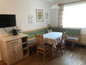 a dining room with a table and chairs and a television at Schmiedlehnerhof in Birnberg