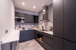 a kitchen with black cabinets and white counter tops at Buckingham Court in Cheltenham