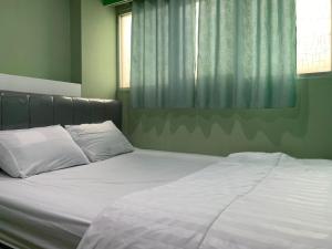 een bed met witte lakens en kussens in een slaapkamer bij RedLiving Apartemen Sentra Timur - YN Idea Property Tower Kuning in Jakarta