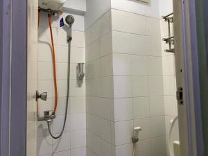 een douche met een oranje slang in de badkamer bij RedLiving Apartemen Sentra Timur - YN Idea Property Tower Kuning in Jakarta