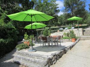 una mesa y sillas bajo una sombrilla verde en Chambres & Tables d'hôtes Le Pech Grand en Saint-Sozy