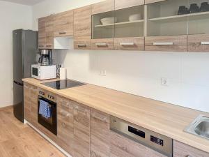 eine Küche mit Holzschränken und einer Mikrowelle in der Unterkunft T&K Apartments - Duisburg - 3 Zimmer Apartment in Duisburg