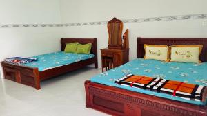a bedroom with two beds and a night stand at Phúc Nguyễn House in Lagi