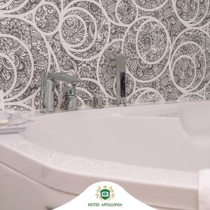 uma casa de banho com um lavatório branco e um papel de parede preto e branco em Hotel Apollonia em Gjakove