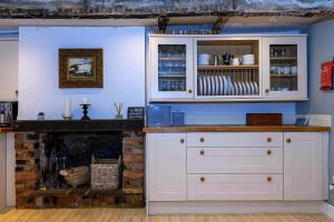 a kitchen with white cabinets and a fireplace at Finest Retreats - Millgate in Richmond