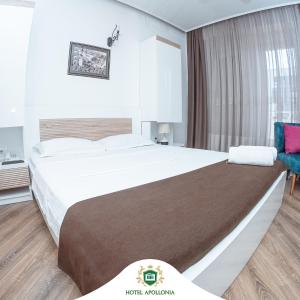 um quarto de hotel com uma cama grande e uma cadeira em Hotel Apollonia em Gjakove