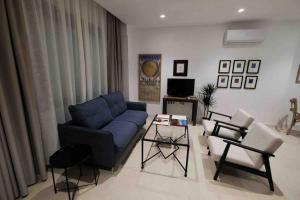 a living room with a blue couch and chairs at CoLet Apartamento in Seville